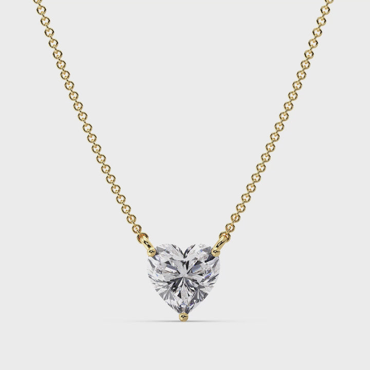 A close-up video showcasing the Yellow Gold variant of the 2.00 Carat Heart-Shaped Lab-Grown Diamond Solitaire Pendant Necklace. The pendant features a dazzling IGI Certified 2.00ct heart-cut diamond with E color and VS clarity, set in a secure prong setting. The warm 18K Yellow Gold frame enhances the brilliance of the diamond, creating a timeless and elegant look. The video captures the pendant's intricate details and radiant sparkle, accompanied by a delicate chain, perfect for any special occasion.